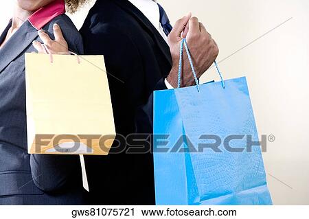 Mid section view of a businessman and a businesswoman holding shopping bags View Large Photo Image Stock Image - Mid section view of a businessman and a businesswoman holding shopping bags. Fotosearch