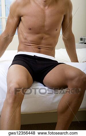 Mid section view of a mid adult man sitting on a bed View Large Photo Image Stock Photo - Mid section view of a mid adult man sitting on a bed. Fotosearch