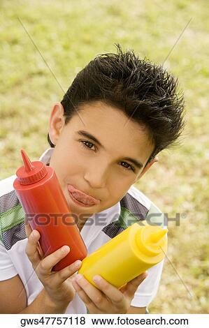 Portrait of a boy holding a ketchup and mustard bottle View Large Photo Image Stock Photo - Portrait of a boy holding a ketchup and mustard bottle. Fotosearch