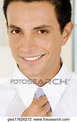 Stock Image - Portrait of a businessman adjusting his tie. Fotosearch