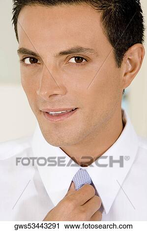 Stock Image - Portrait of a businessman adjusting his tie. Fotosearch
