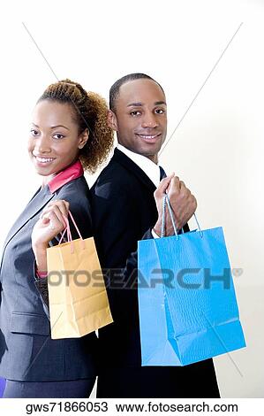 Stock Image - Portrait of a businessman and a businesswoman holding shopping bags. Fotosearch