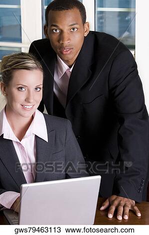 Portrait of a businessman and a businesswoman in front of a laptop View Large Photo Image Stock Image - Portrait of a businessman and a businesswoman in front of a laptop. Fotosearch