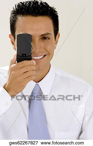 Portrait of a businessman hiding his eye with a mobile phone View Large Photo Image Stock Photo - Portrait of a businessman hiding his eye with a mobile phone. Fotosearch