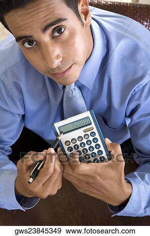 Portrait of a businessman holding a calculator and a pen View Large Photo Image Stock Photo - Portrait of a businessman holding a calculator and a pen. Fotosearch