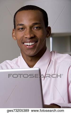 Stock Photo - Portrait of a businessman in front of a laptop. Fotosearch