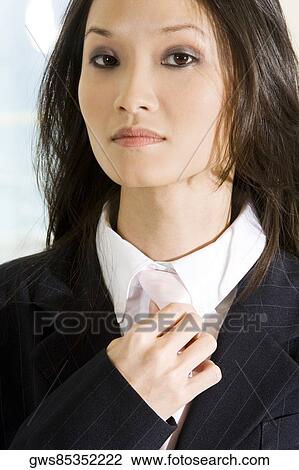Stock Image - Portrait of a businesswoman adjusting her tie. Fotosearch
