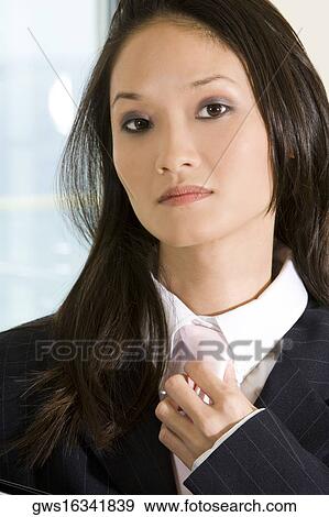 Stock Photo - Portrait of a businesswoman adjusting her tie. Fotosearch