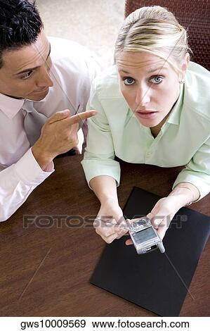 Stock Photo - Portrait of a businesswoman holding a mobile phone with a businessman beside her. Fotosearch