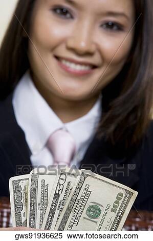 Stock Photography - Portrait of a businesswoman holding one hundred dollar bills. Fotosearch
