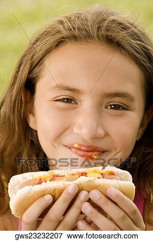 Portrait of a girl eating a hotdog View Large Photo Image Stock Photo - Portrait of a girl eating a hotdog. Fotosearch