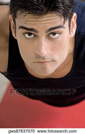 Stock Image - Portrait of a mid adult man doing push-ups. Fotosearch
