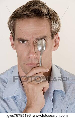 Portrait of a mid adult man holding a spoon in front of his eye View Large Photo Image Stock Photograph - Portrait of a mid adult man holding a spoon in front of his eye. Fotosearch