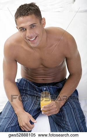Stock Photography - Portrait of a young man holding a glass of juice. Fotosearch