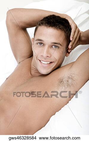 Portrait of a young man lying on a bed smiling View Large Photo Image Picture - Portrait of a young man lying on a bed smiling. Fotosearch