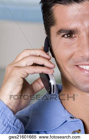 Portrait of a young man talking on a mobile phone View Large Photo Image Stock Photography - Portrait of a young man talking on a mobile phone. Fotosearch