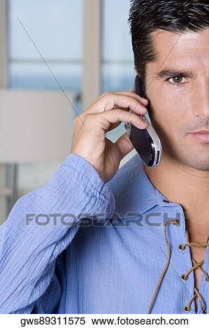 Portrait of a young man talking on a mobile phone View Large Photo Image Stock Photography - Portrait of a young man talking on a mobile phone. Fotosearch