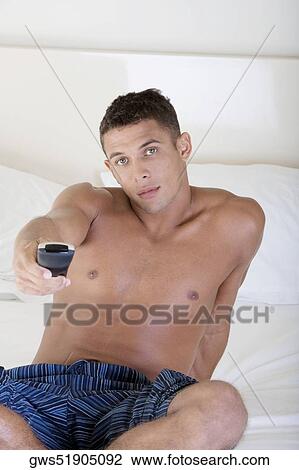 Stock Image - Portrait of a young man using a remote control. Fotosearch