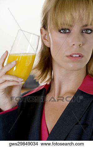 Portrait of a young woman holding a glass of orange juice View Large Photo Image Picture - Portrait of a young woman holding a glass of orange juice. Fotosearch