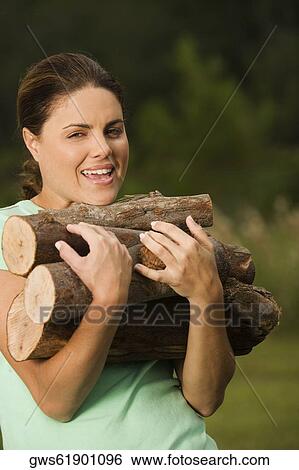 Portrait of a young woman holding a heap of wood logs View Large Photo Image Stock Photograph - Portrait of a young woman holding a heap of wood logs. Fotosearch