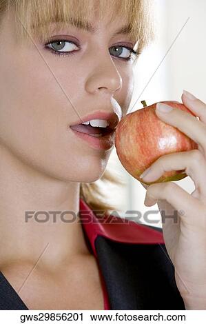 Stock Image - Portrait of a young woman holding an apple. Fotosearch