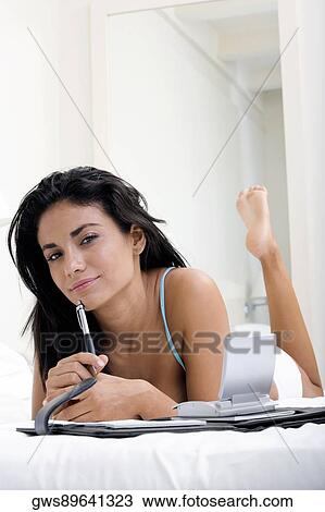 Portrait of a young woman lying on a bed in front of a personal organizer View Large Photo Image Stock Image - Portrait of a young woman lying on a bed in front of a personal organizer. Fotosearch