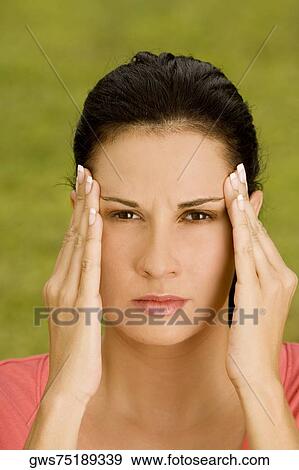 Portrait of a young woman rubbing her temples View Large Photo Image Stock Photo - Portrait of a young woman rubbing her temples. Fotosearch
