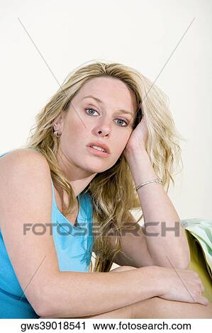 Portrait of a young woman sitting on a couch View Large Photo Image Stock Image - Portrait of a young woman sitting on a couch. Fotosearch