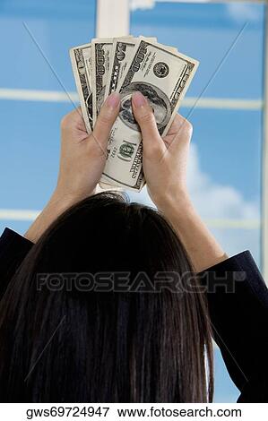 Rear view of a businesswoman holding American paper currency View Large Photo Image Stock Photo - Rear view of a businesswoman holding American paper currency. Fotosearch