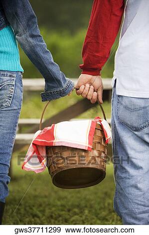 Rear view of a couple holding a picnic basket View Large Photo Image Stock Photo - Rear view of a couple holding a picnic basket. Fotosearch