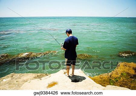 Rear view of a man fishing from a rock, Pacific Ocean, Coronado Reefs, San Diego, California, USA View Large Photo Image Stock Photograph - Rear view of a man fishing from a rock, Pacific Ocean, Coronado Reefs, San Diego, California, USA. Fotosearch