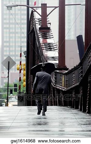 Rear view of a man walking across a bridge, Chicago, Illinois, USA View Large Photo Image Stock Photo - Rear view of a man walking across a bridge, Chicago, Illinois, USA. Fotosearch