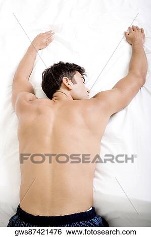 Rear view of a mid adult man sleeping on a bed View Large Photo Image Stock Photograph - Rear view of a mid adult man sleeping on a bed. Fotosearch