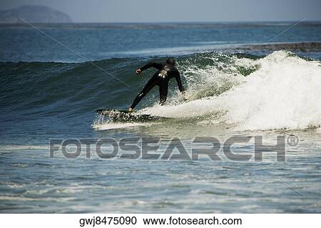Stock Image - Rear view of a person surfing. Fotosearch