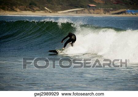 Stock Photo - Rear view of a person surfing. Fotosearch