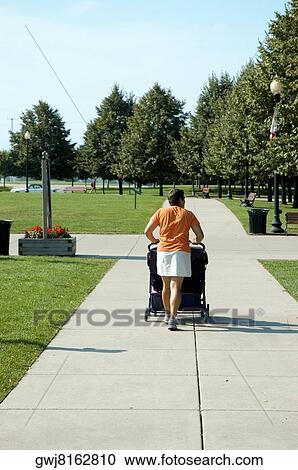 Stock Image - Rear view of a woman pushing a baby stroller, Gateway Park, Chicago, Illinois, USA. Fotosearch