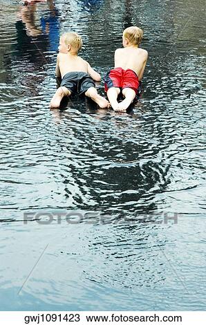 Rear view of two boys lying down in water View Large Photo Image Stock Image - Rear view of two boys lying down in water. Fotosearch
