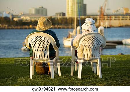 Stock Image - Rear view of two people sitting on a waterfront, San Diego Bay, San Diego, California, USA. Fotosearch