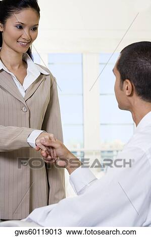 Side profile of a businessman shaking hands with a businesswoman View Large Photo Image Stock Image - Side profile of a businessman shaking hands with a businesswoman. Fotosearch