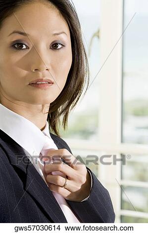 Side profile of a businesswoman adjusting her tie View Large Photo Image Picture - Side profile of a businesswoman adjusting her tie. Fotosearch