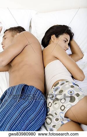 Side profile of a young couple lying on a bed View Large Photo Image Stock Image - Side profile of a young couple lying on a bed. Fotosearch