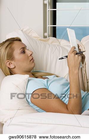 Side profile of a young woman lying on a couch reading a book View Large Photo Image Stock Photo - Side profile of a young woman lying on a couch reading a book. Fotosearch