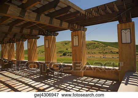 Stock Photo - Tables and chairs in a trellised corridor. Fotosearch