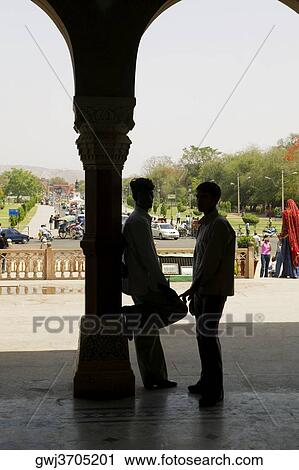 Two people standing against a column View Large Photo Image Stock Image - Two people standing against a column. Fotosearch