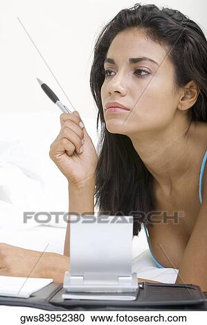 Young woman lying on a bed in front of a personal organizer View Large Photo Image Stock Image - Young woman lying on a bed in front of a personal organizer. Fotosearch