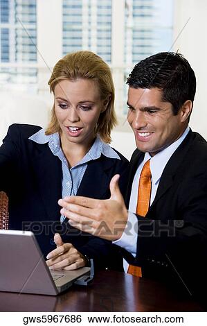 Stock Photograph - Businessman and a businesswoman looking at a laptop. Fotosearch