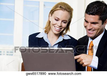 Businessman and a businesswoman working on a laptop View Large Photo Image Stock Image - Businessman and a businesswoman working on a laptop. Fotosearch