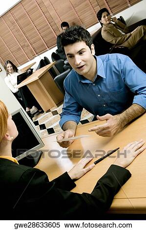 Stock Photography - Businessman talking with a businesswoman in an office. Fotosearch