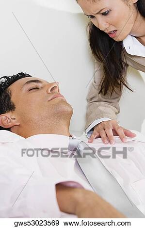 Stock Photo - Businesswoman bending over a businessman on a couch. Fotosearch