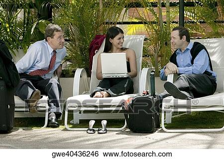 Businesswoman holding a laptop and talking with two businessmen View Large Photo Image Stock Photograph - Businesswoman holding a laptop and talking with two businessmen. Fotosearch